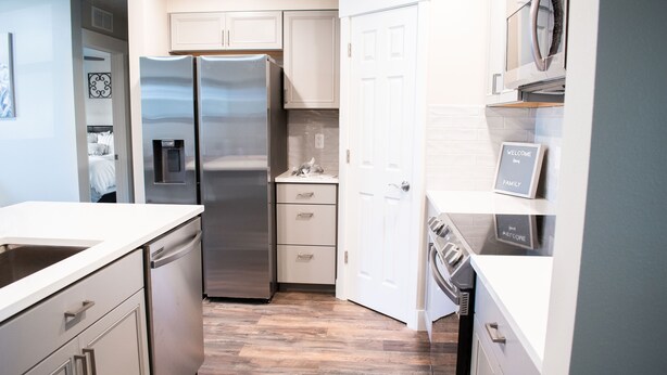 A modern kitchen with stainless steel appliances, white cabinetry, and a wooden floor. - New family-sized home in the heart of old-town Nampa -- walking distance to NNU! (Nampa)