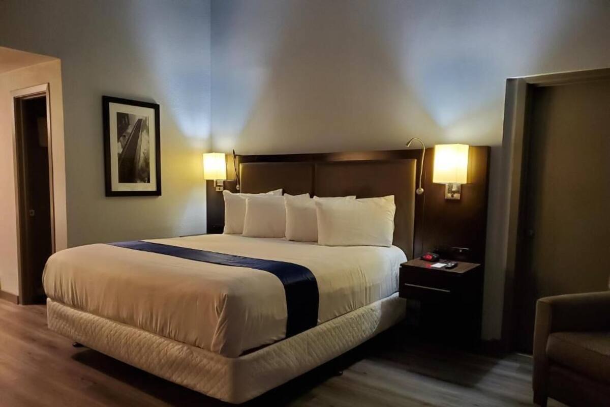 A hotel room with a large bed, two bedside tables, and a nightstand.