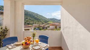 Ein Balkon mit Frühstückstisch, Blick auf ein Dorf und ein Berg in der Ferne.