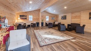 Un interior de madera con varias zonas de estar, una alfombra central y obras de arte en las paredes.
