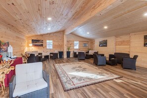A wooden interior with multiple seating areas, a central rug, and artwork on the walls.
