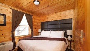 A wooden cabin bedroom with a bed, two bedside lamps, a window with curtains, and a ceiling light. - Family Log Cabin Near Sauna White Mountains (Bethlehem)