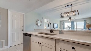 A modern kitchen with a built-in dishwasher, a large sink, and a contemporary light fixture above the countertop.