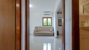 A hallway with a wooden door, a beige sofa, a window, and a bathroom with a mirror and sink. - Panoramic Apartments Anić - Superior Two Bedroom Apartment with Terrace and Sea View (Blato)
