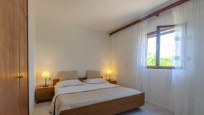 A bedroom with a wooden bed, two bedside tables with lamps, a window with sheer curtains, and a wooden wardrobe. - Panoramic Apartments Anić - Superior Two Bedroom Apartment with Terrace and Sea View (Blato)
