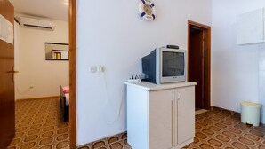 Une pièce avec un téléviseur posé sur un meuble, un sol à motifs et un panneau d’accueil accroché au mur.