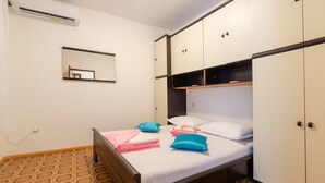 Une chambre à coucher comprenant un lit, une armoire, un miroir et un appareil de climatisation.