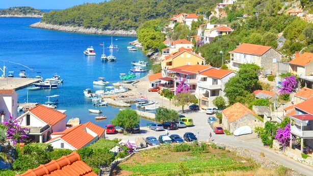 Un village côtier avec des maisons, un port de plaisance et des bateaux.