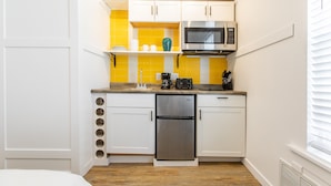 A compact kitchen with white cabinets, a stainless steel refrigerator, a microwave, and a yellow backsplash. - 8032-3 blocks to Mayo-SALE Cute Studio on Main Floor 8032 (Rochester)