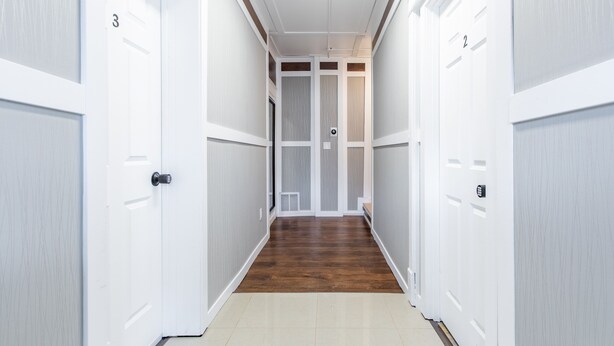 A hallway with white doors numbered 2 and 3, leading to a room with a wooden floor and a window. - 8032-3 blocks to Mayo-SALE Cute Studio on Main Floor 8032 (Rochester)