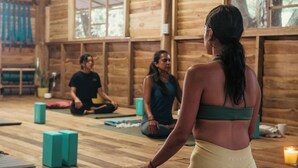 A wooden cabin interior with a yoga class in progress, featuring participants seated on mats, a wooden floor, and a large window. - RusTeak Living Boutique Hotel Mango Studio - a Refuge in Nature (Provincia de Guanacaste)