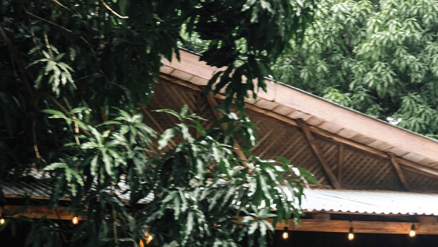 A person standing by a pool with a wooden deck and a thatched-roof structure in the background. - RusTeak Living Boutique Hotel Mango Studio - a Refuge in Nature (Provincia de Guanacaste)