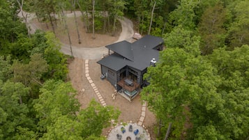 Escape to a secluded cabin nestled in the forest, featuring a spacious deck with a fire pit and seating area.