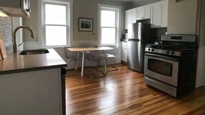 A compact kitchen with a sink, stove, refrigerator, and a dining area with a table and chairs.