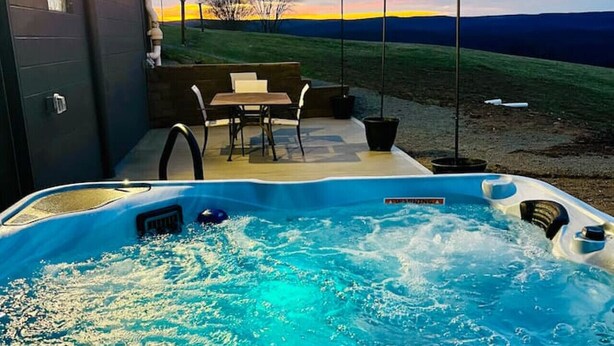 Ein Whirlpool mit Blick auf ein grünes Feld und ein Gebäude im Hintergrund.