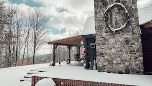 Un bâtiment en pierre doté d’un patio couvert et d’une terrasse recouverte de neige.