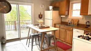 A kitchen with wooden cabinets, a refrigerator, a stove, and a dining area with stools.