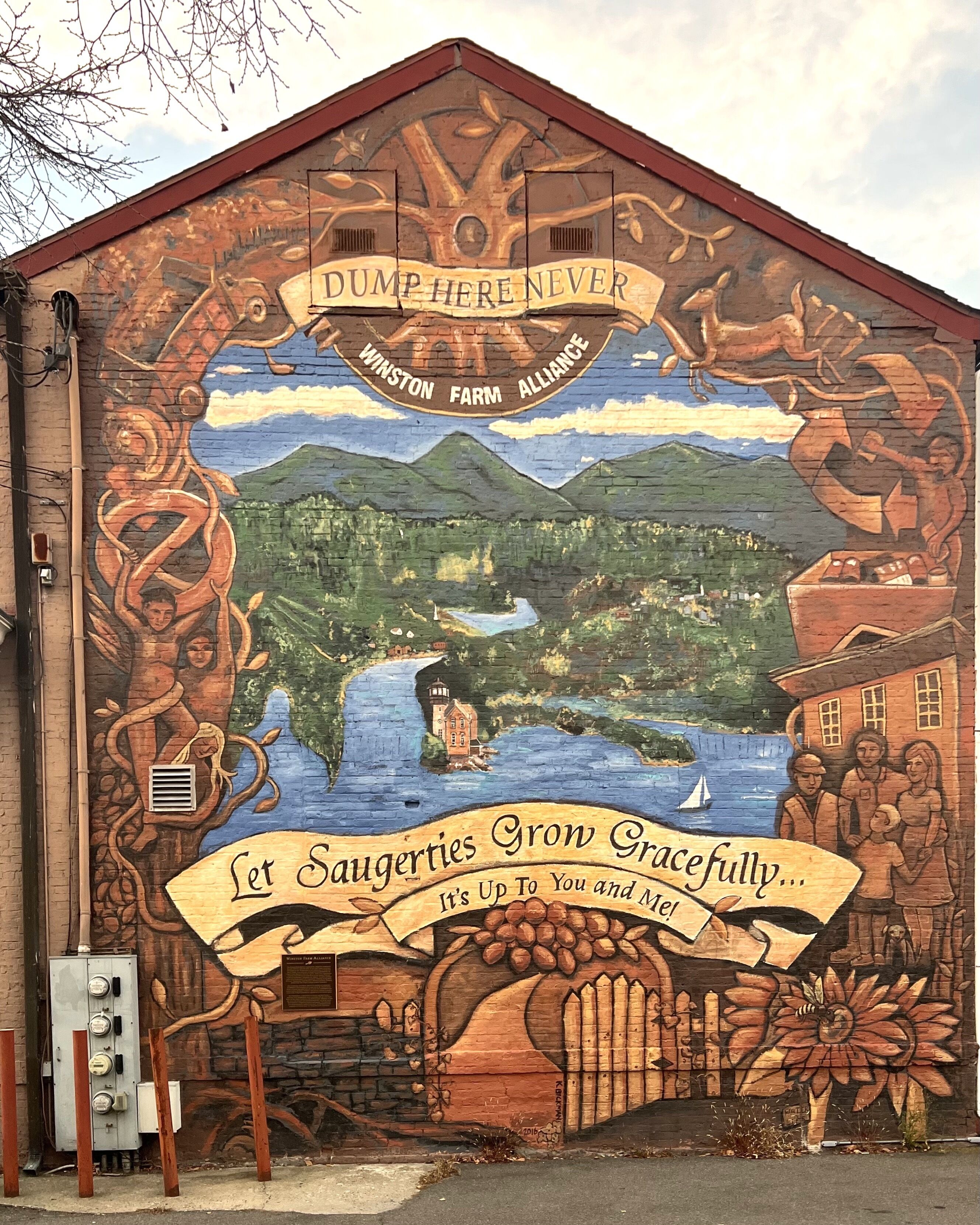 A mural on a building with a warning sign, a landscape, and a group of people.