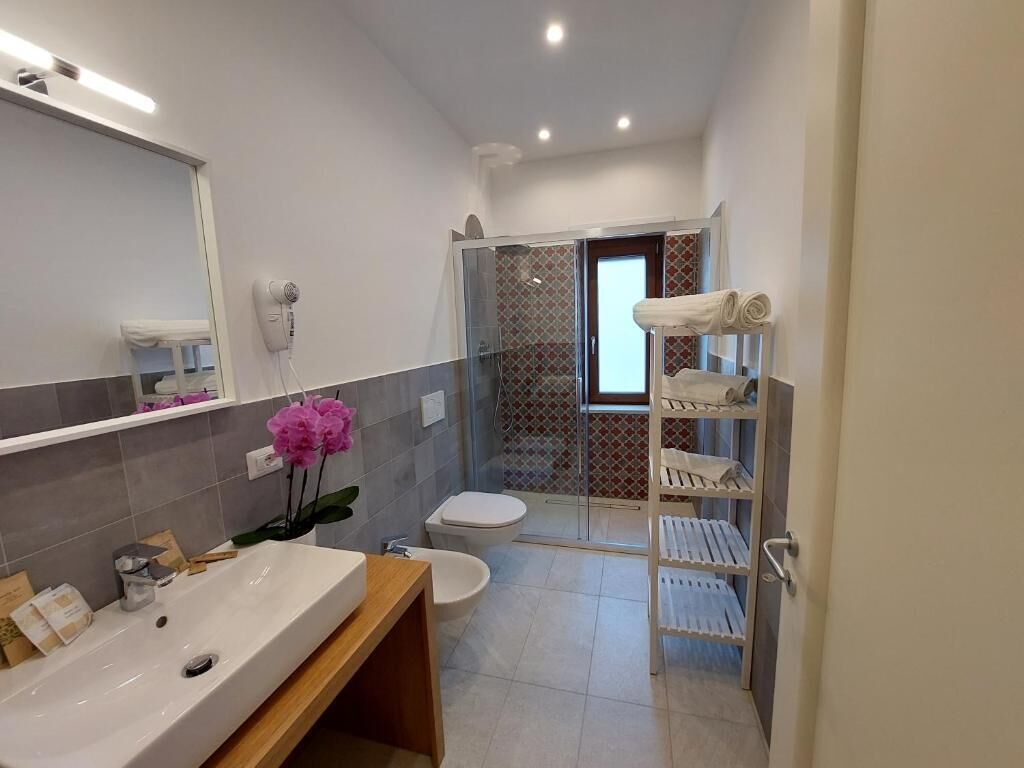 A modern bathroom with a large sink, a toilet, a shower area, and a glass door leading to a balcony.