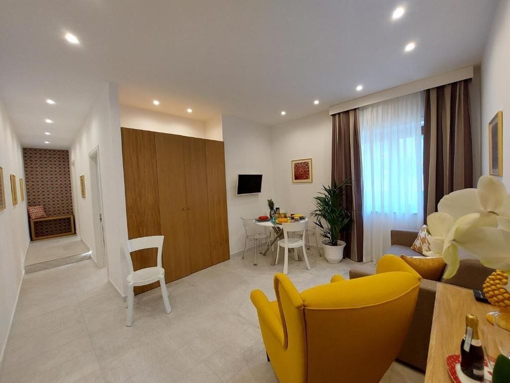 Una sala de estar moderna con comedor, un armario de madera, un televisor y una planta en maceta.