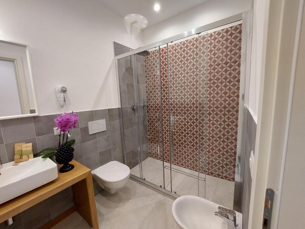 A modern bathroom with a glass-enclosed shower, a white sink, and a toilet.