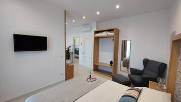 A modern bedroom with a bed, a TV, a chair, and a small table.