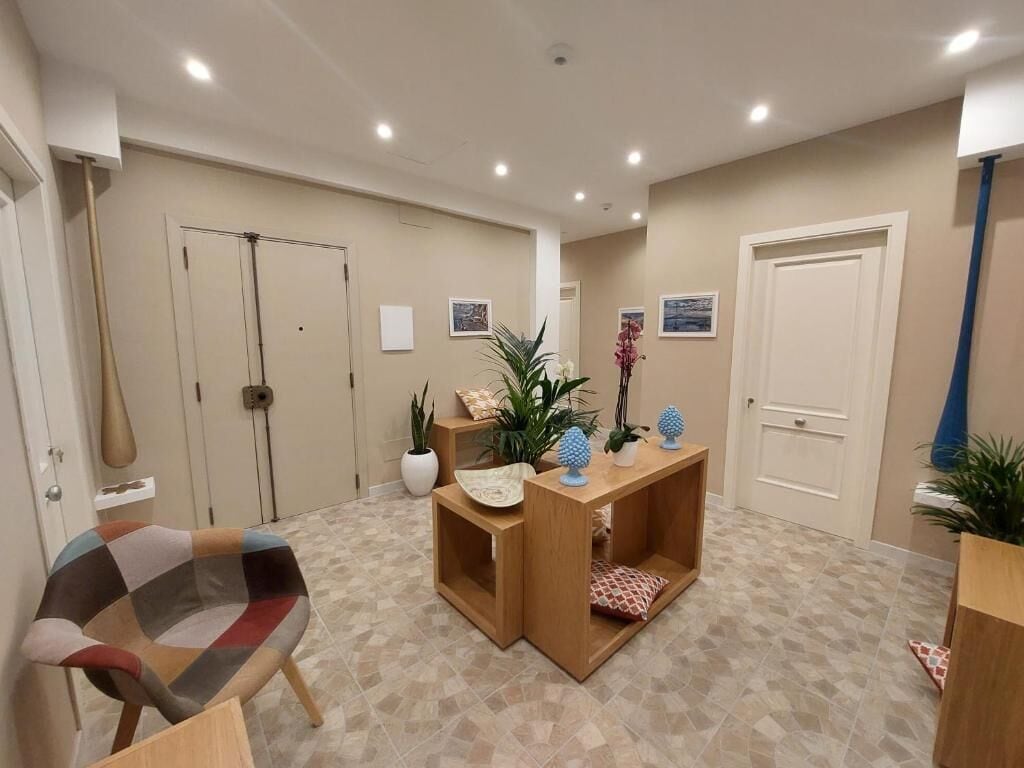 Una habitación con una consola de madera, un sillón colorido y un suelo estampado.