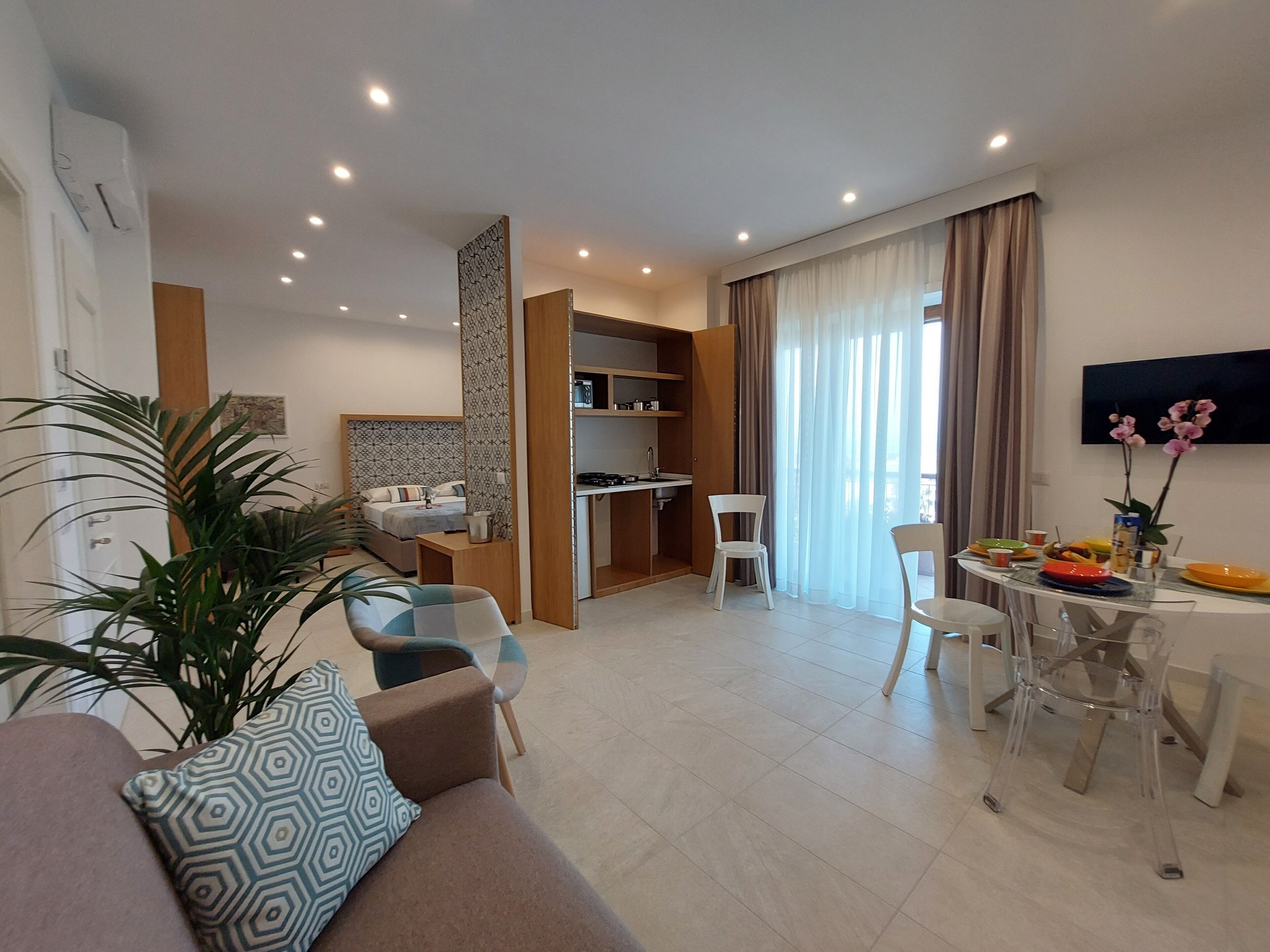 Una sala de estar moderna con sofá, mesa de comedor, sillas y una zona de cocina.
