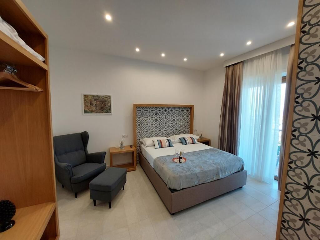 Ein modernes Schlafzimmer mit einem Bett, einem Sessel, einem Nachttisch und einem Kleiderschrank.