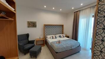 Ein modernes Schlafzimmer mit einem Bett, einem Sessel, einem Nachttisch und einem Kleiderschrank.