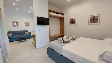 A modern bedroom with a bed, a sofa, a TV, and artwork on the walls.