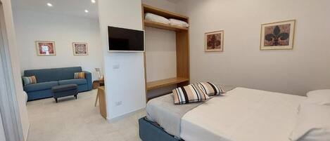Een moderne slaapkamer met een bed, een bank, een televisie en kunstwerken aan de wanden.