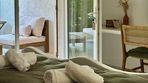 A room with a bed, a chair, a sofa, and a sliding glass door leading to an outdoor area. - Hotel Palombaggia (Porto-Vecchio)