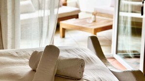 A hotel room with a bed, a wooden table, and a white chair. - Hotel Palombaggia (Porto-Vecchio)