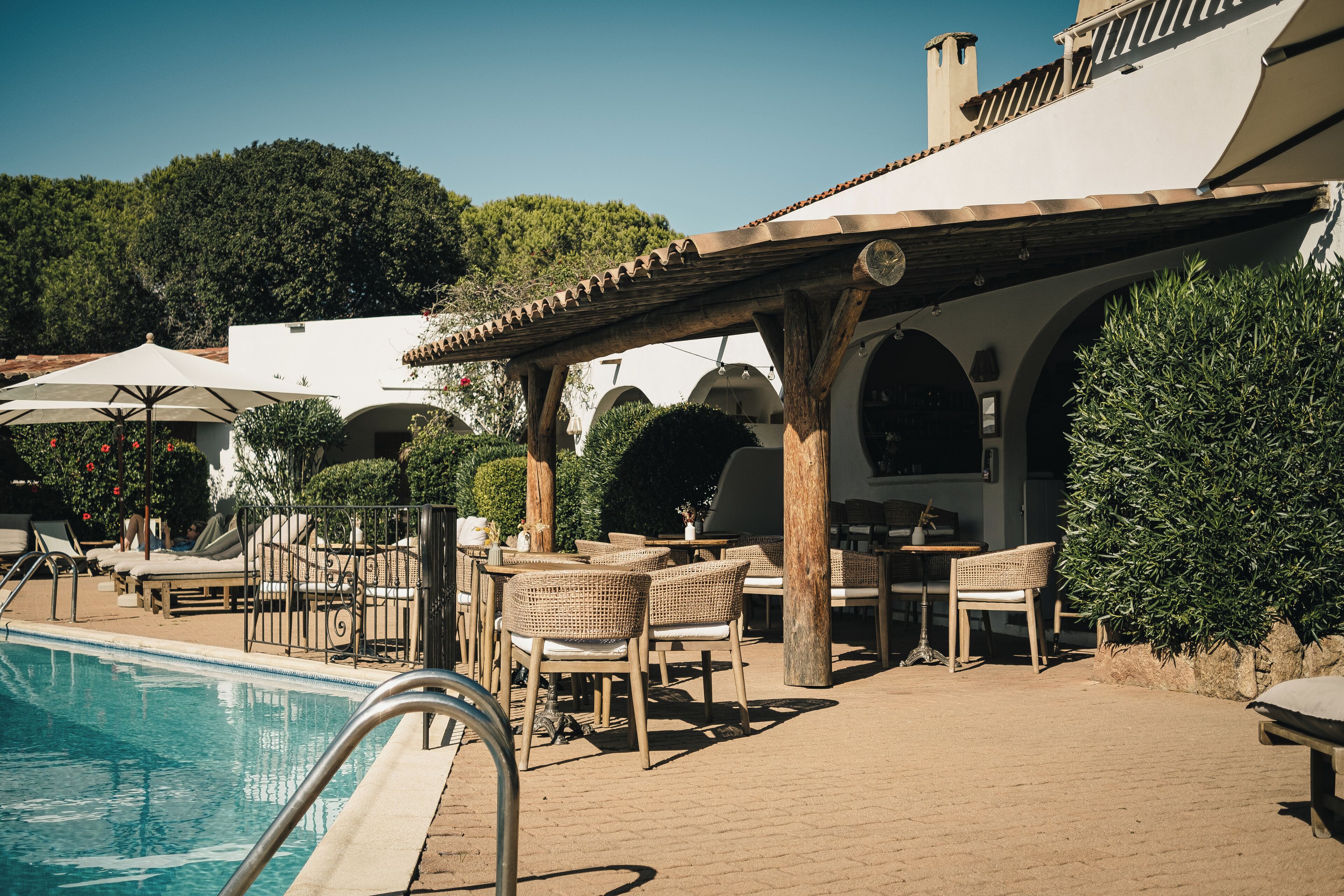 Ein Poolbereich mit Liegestühlen, einer Pergola und Gartenmöbeln.