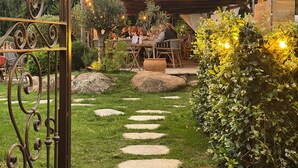 An outdoor dining area with stone pathways, rustic wooden furniture, and string lights. - Hotel Palombaggia (Porto-Vecchio)
