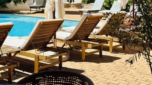 A poolside area with lounge chairs and umbrellas, surrounded by greenery and hills. - Hotel Palombaggia (Porto-Vecchio)