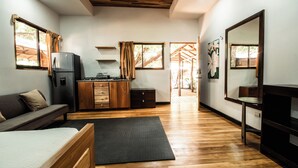 A modern room with a bed, a sofa, a kitchen area, and a dining table.