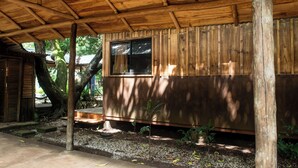 A wooden cabin with a window, a wooden deck, and a small garden area.