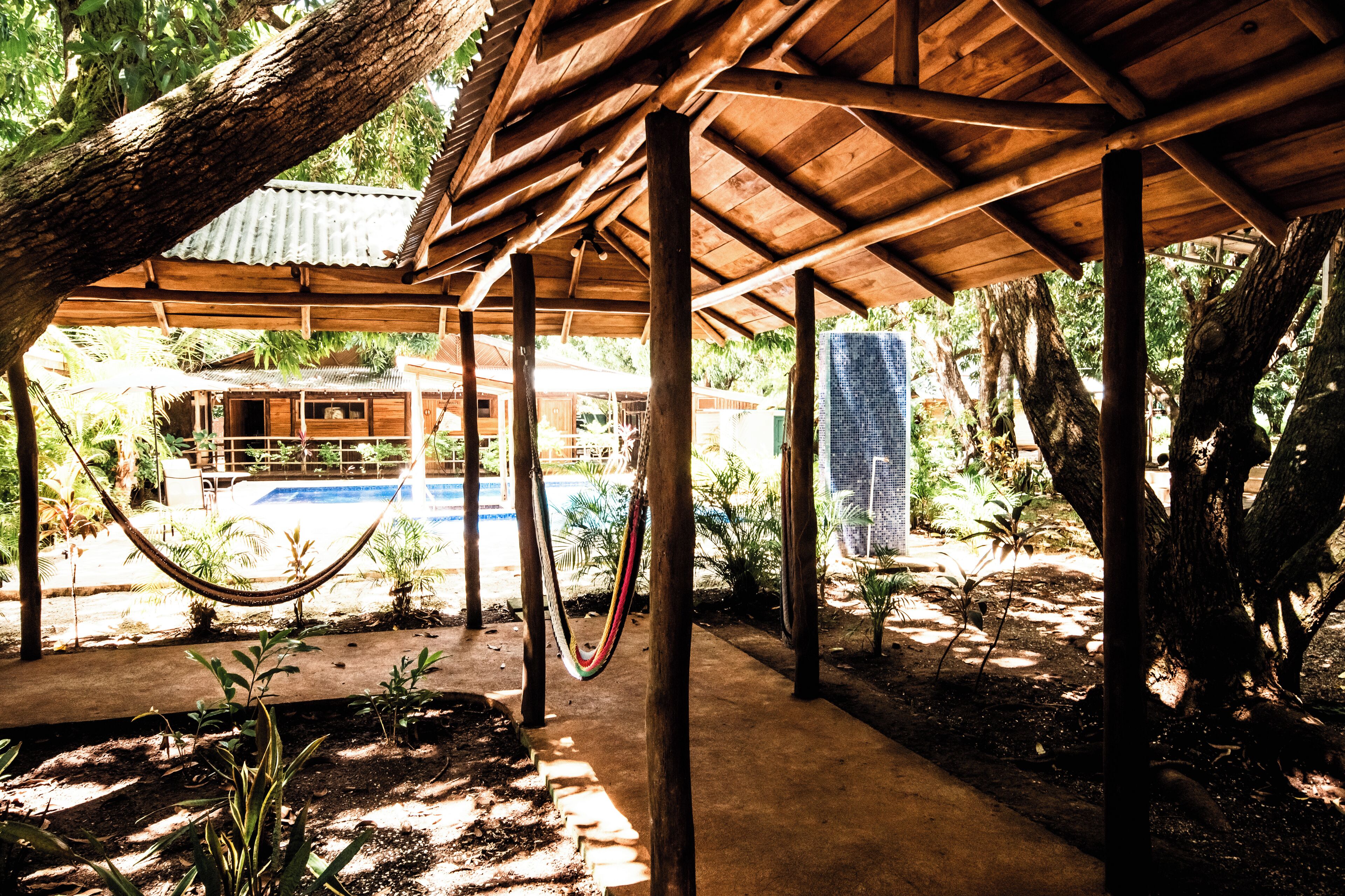 Une structure en bois avec une piscine et un hamac.