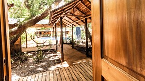 A wooden structure with a roof, a hammock, and a pool area.