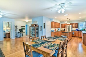 A spacious kitchen with wooden cabinets, a central island, and a dining area with a floral table runner. - Waterfront Gladwin Home w/ Deck + Fire Pit! (Gladwin)