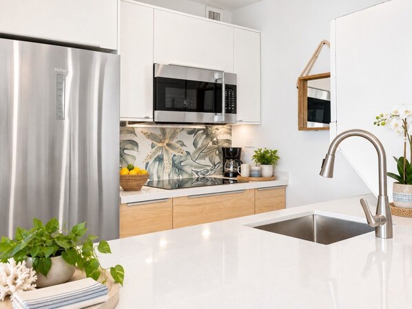 A modern kitchen with a stainless steel refrigerator, a microwave, and a sink with a contemporary faucet. - Beachfront 2b/2b  Walk 2 Eat  Isla Verde Beach (Carolina)