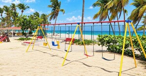 A beach with a swing set, palm trees, and a clear view of the ocean. - Beachfront 2b/2b  Walk 2 Eat  Isla Verde Beach (Carolina)