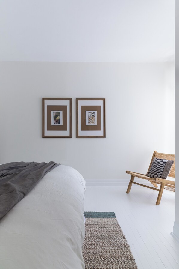 Une chambre à coucher avec un lit, une chaise et deux tableaux encadrés accrochés au mur.