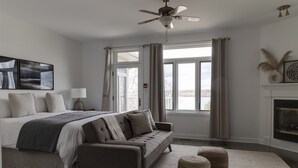 Ein Schlafzimmer mit Bett, Sofa, Kamin und Blick ins Freie.