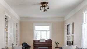 A living room with a piano, two sofas, a coffee table, and a bookshelf. - The Carrington | 5 Bed Victorian | Pool  and  Hot Tub (Prince Edward)