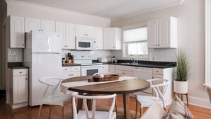 Een moderne keuken met witte kastjes, een centraal eiland met stoelen, een magnetron en een fornuis.