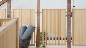 Ein geräumiger Raum mit hoher Decke, Holzbalken und einem großen Korb voller zusammengerollter Matten.