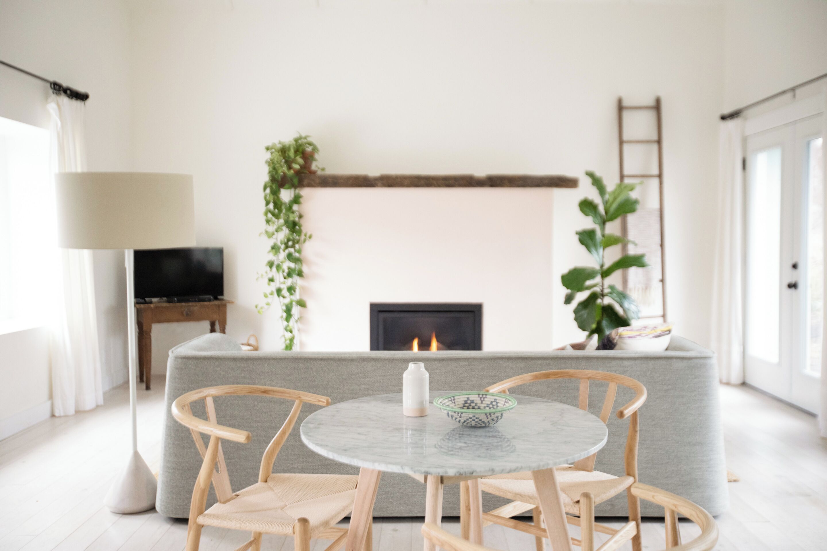 A modern living room with a fireplace, a round table with chairs, a sofa, and a TV.